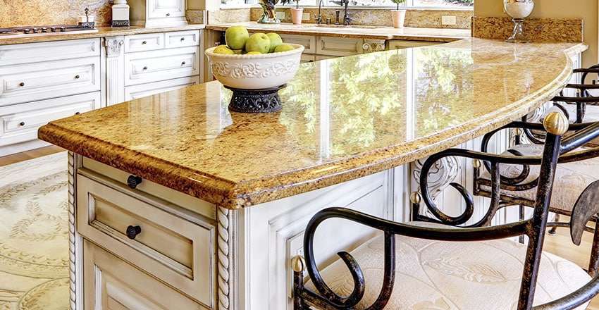 Elegant kitchen with brown granite countertop, vintage chairs and white kitchen cabinets