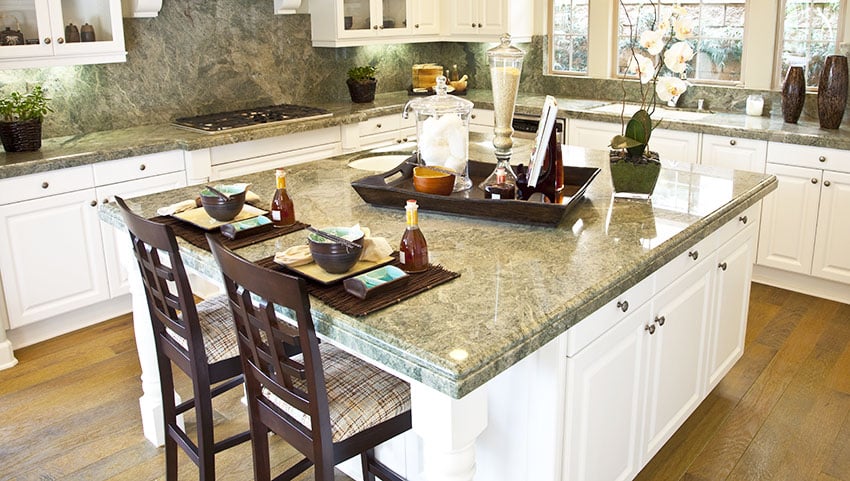 Kitchen breakfast bar with green granite, white kitchen cabinets and upholstered chairs