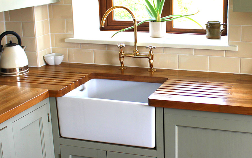 Farmhouse kitchen with sink, double handle faucet, and teak wood countertop
