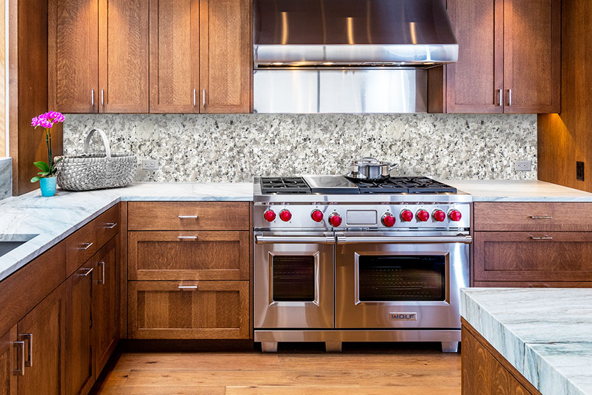 Kitchen with hardwood cabinets large stainless stove and oven granite slab backsplash