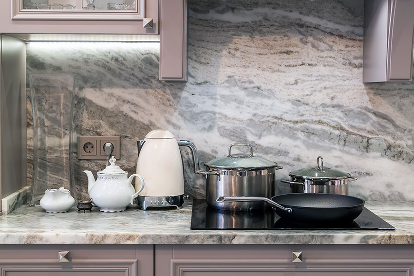 Kitchen with induction cooktop slab backsplash electric kettle teapot