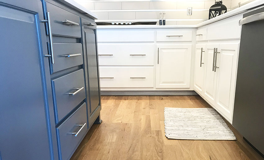 Kitchen with white and blue cabinets with pulls and wooden flooring