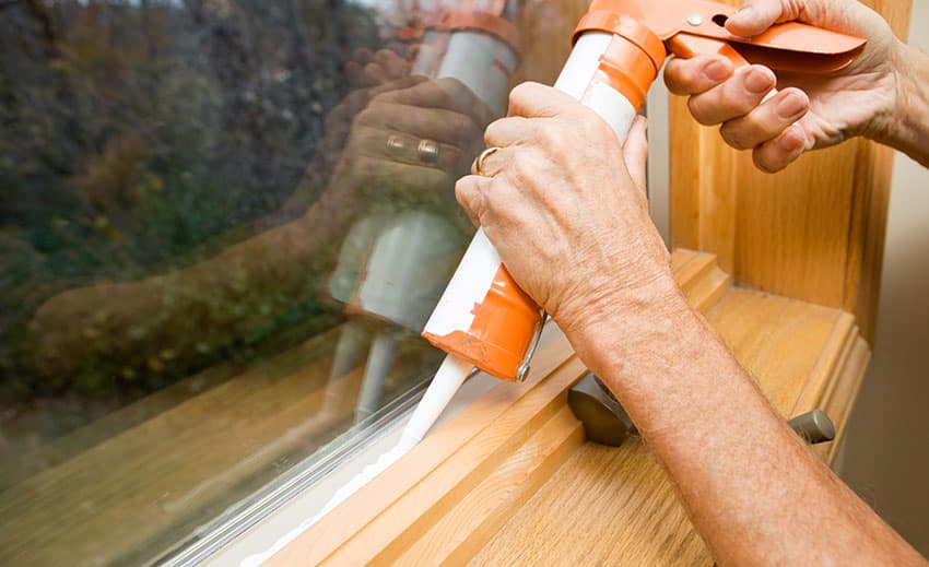 Man applying caulk on window