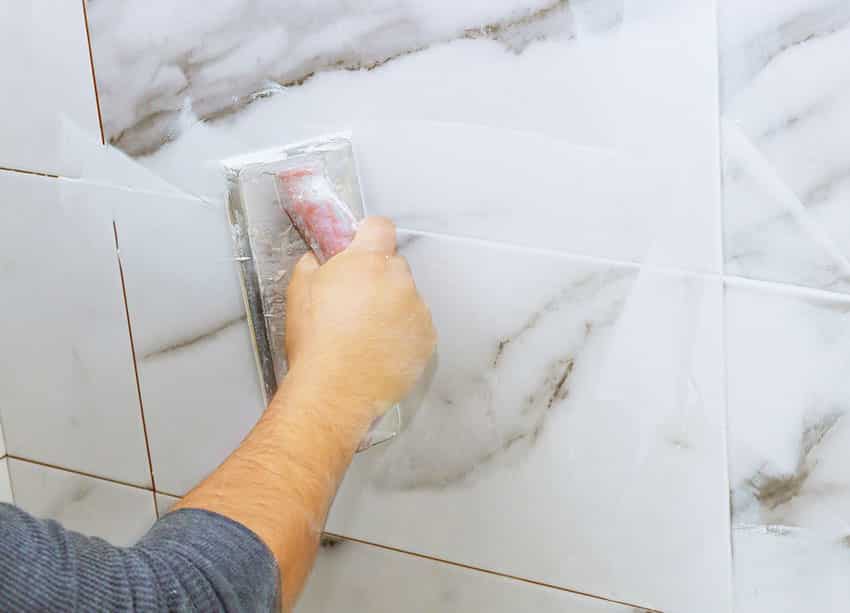 Man applying grout on bathroom wall