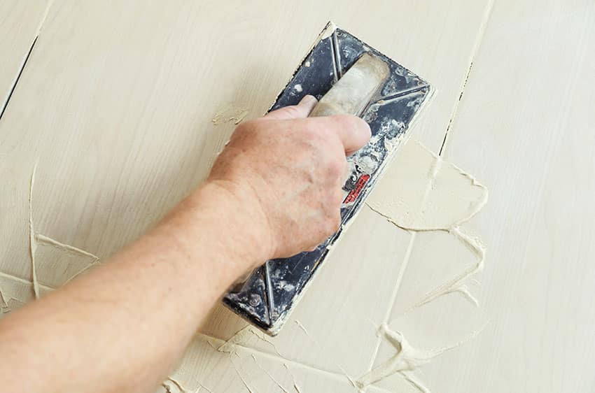 Mason applying tile grout with tile trowel