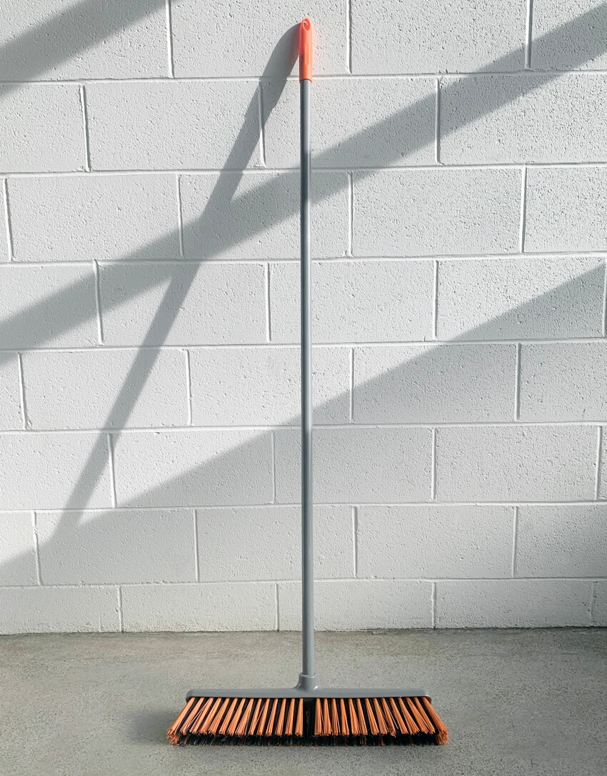 A broom on floor with white wall background