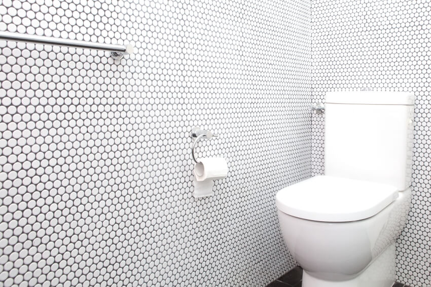 A comfort room with white toilet bowl, towel rack, and penny tile walls and backsplash