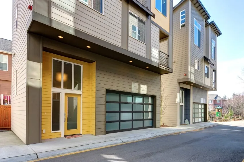Apartment building exterior with asphalt driveway frosted glass garage doors and yellow entrance door