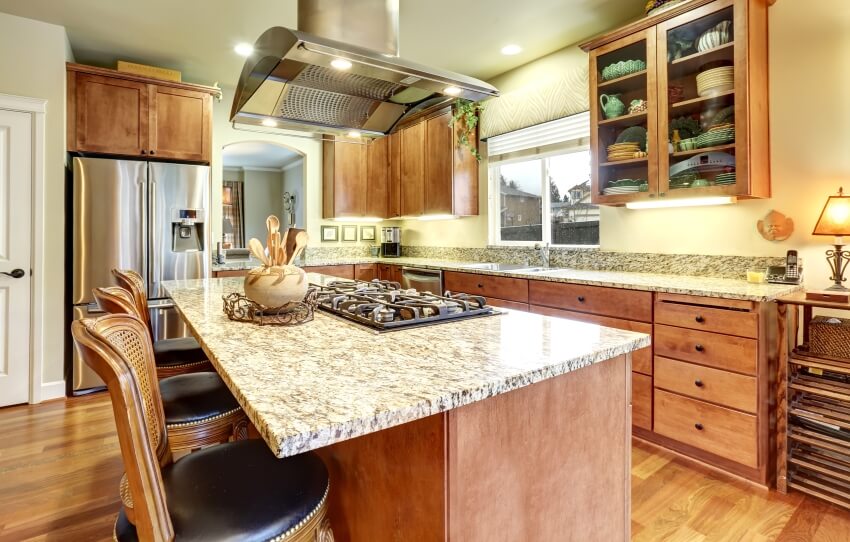 Arts and crafts kitchen design with granite countertops and island with cooktop and chairs