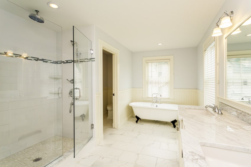 Bathroom with Carrara marble floor, glass door, shower, countertop, mirror, and window