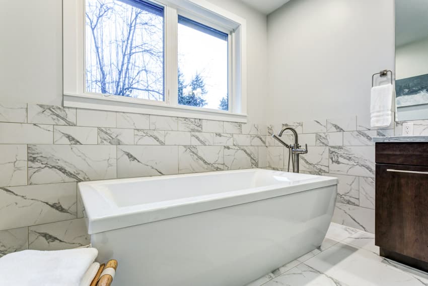 Bathroom with Carrara marble tiles, tub, and windows