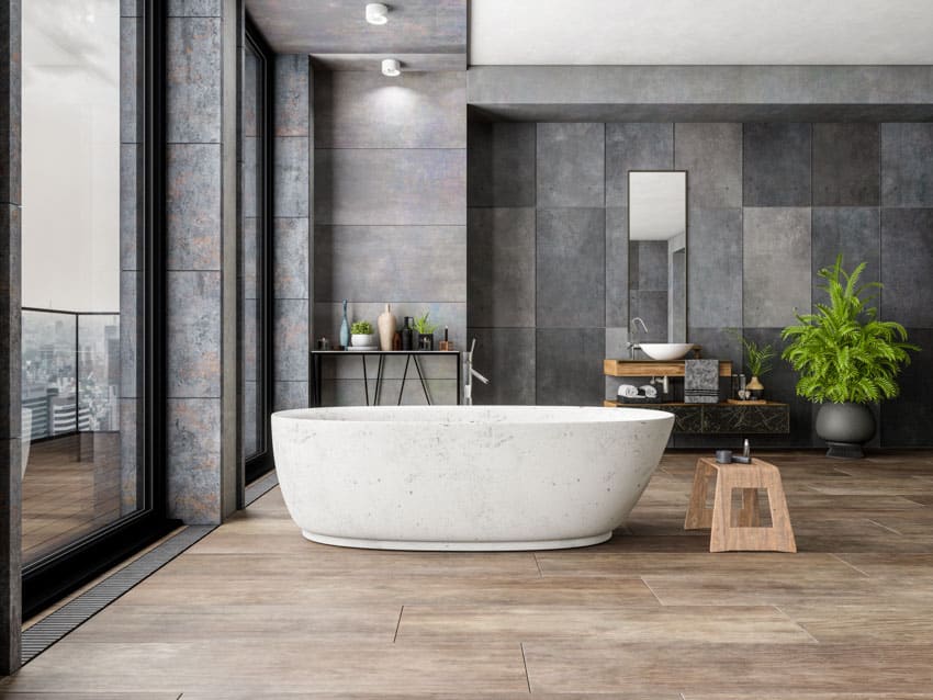 Bathroom with large format backsplash tile, tub, sink, stool, indoor plant, and window