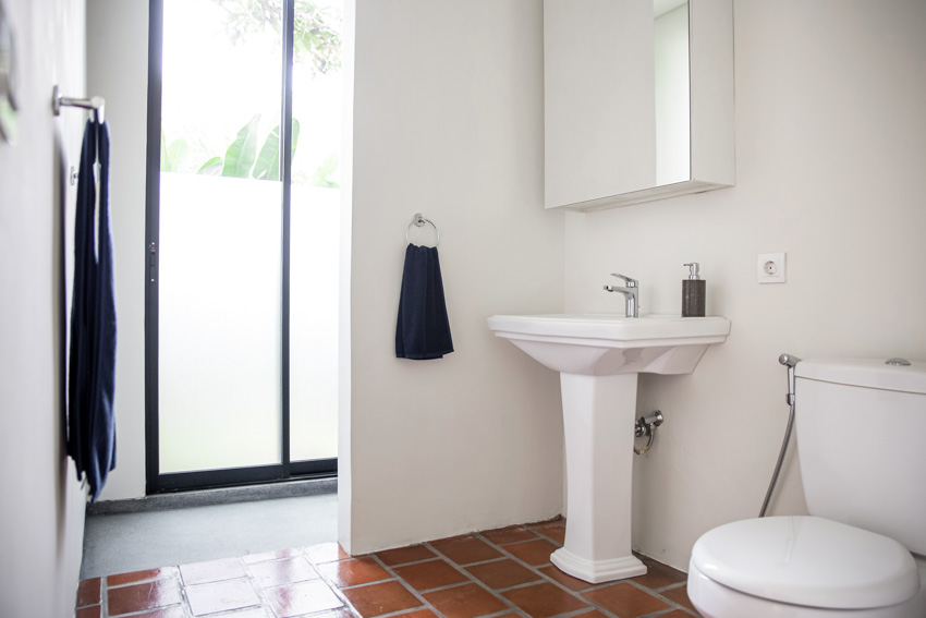 Bathroom with Saltillo tile floors, sink, mirror, toilet, and towel holder