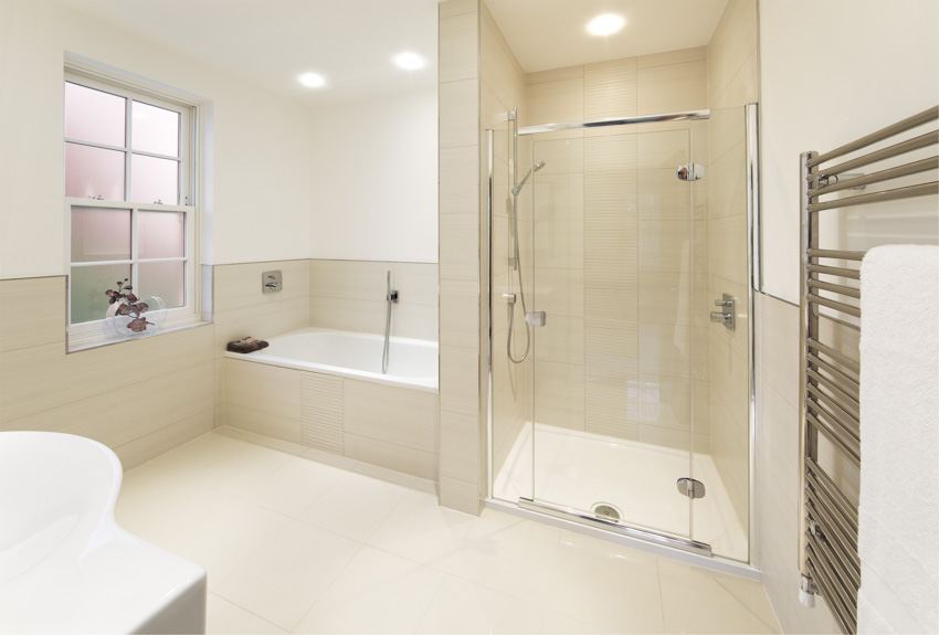 Shower area with glass walls, alcove tub and rack for towels
