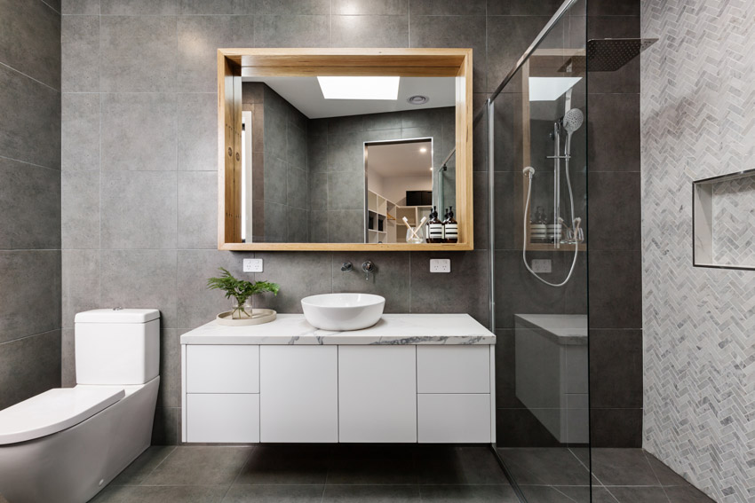 Bathroom with shower, unglazed porcelain tile floor, vanity area, mirror, countertop, sink, and toilet