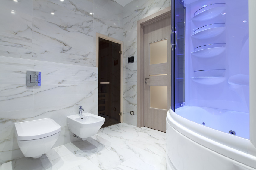 Bathroom with toilet, bidet, tub, glazed porcelain tile wall, and floor