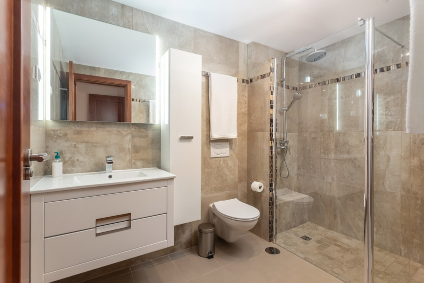 Bathroom with unglazed porcelain tile shower, vanity mirror, sink, cabinet, drawer, and glass enclosure