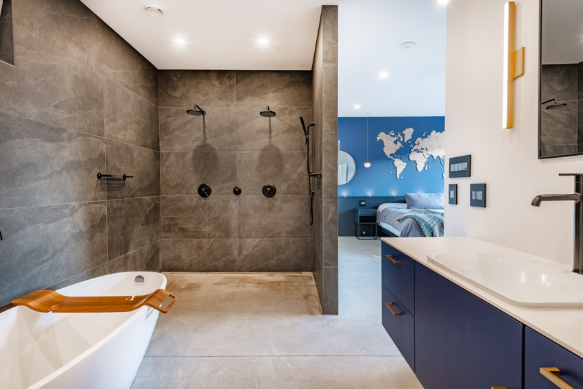 Bathroom with unglazed porcelain tile shower, tub, mirror, sink, countertop, and cabinets