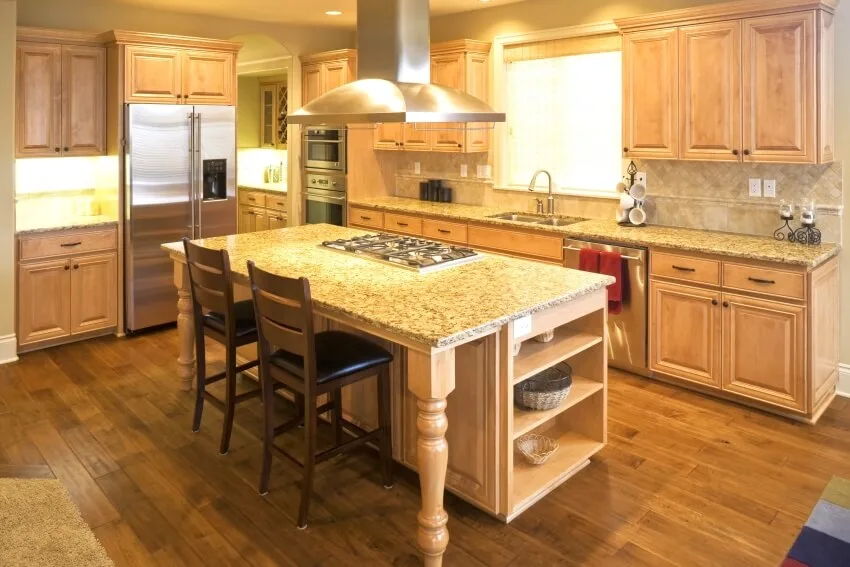 Beautiful kitchen with hardwood floors, brown granite countertops, and island with cooktop 