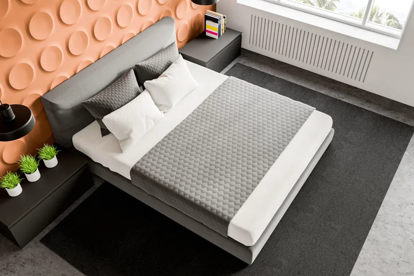 Bedroom with mattress cover, pillows, nightstand, headboard, and windows
