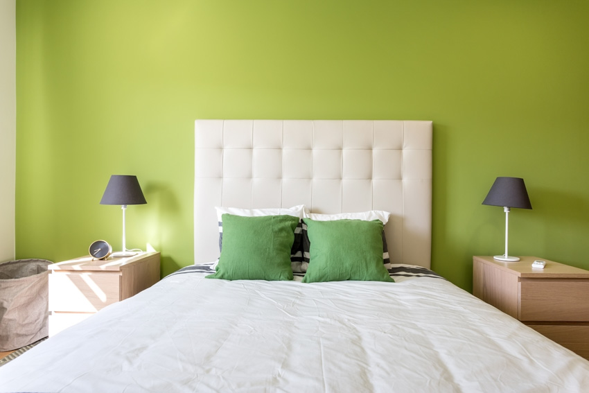 Bedroom with apple green wall, headboard, pillows, nightstands, and lamps
