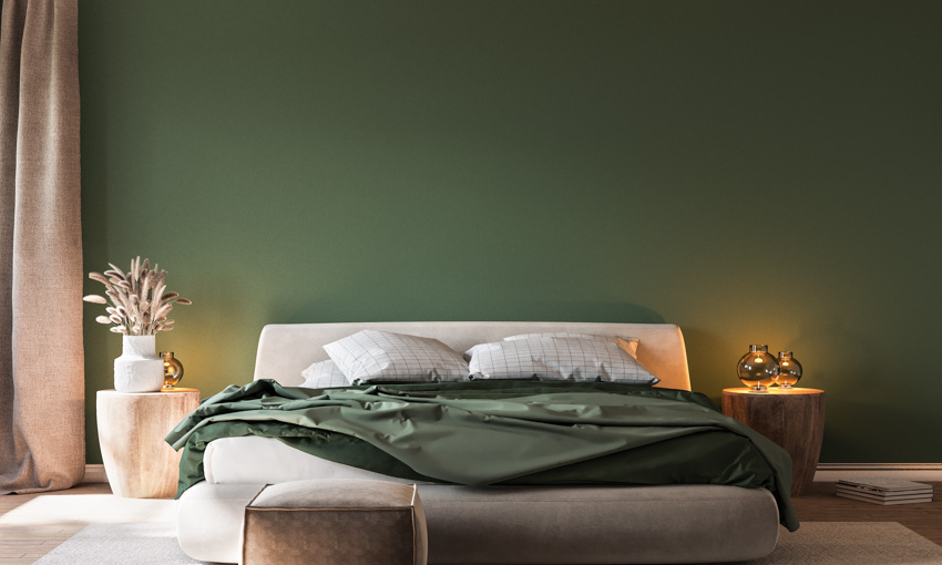 Bedroom with taupe bed, green sheets and wood side table