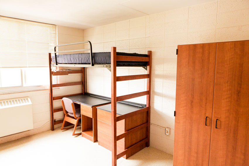 Bedroom with bed and built in desk and windows with blinds