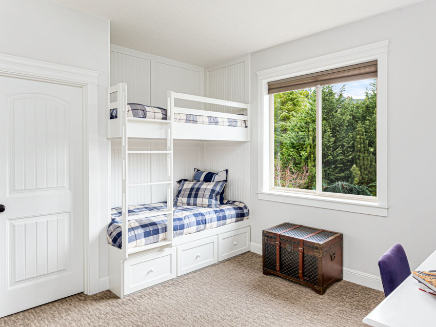 Bedroom with white walls, window, pillows, and bottom bunk drawer