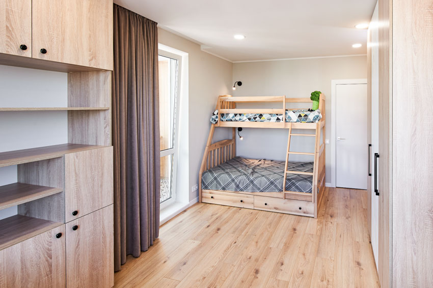 Bedroom with taupe curtains, cabinets, white door anmd bd