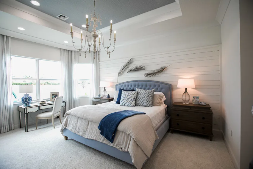 Bedroom with chandelier, headboard, bedding, nightstand, lamp, chandelier, desk, chair, window, and curtain