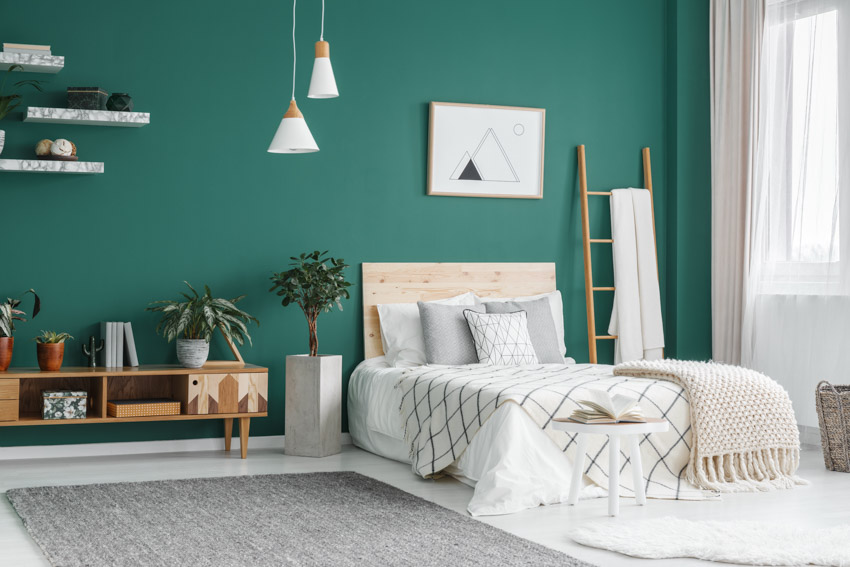 Bedroom with emerald wall, bed, headboard, floating shelves and towel rack