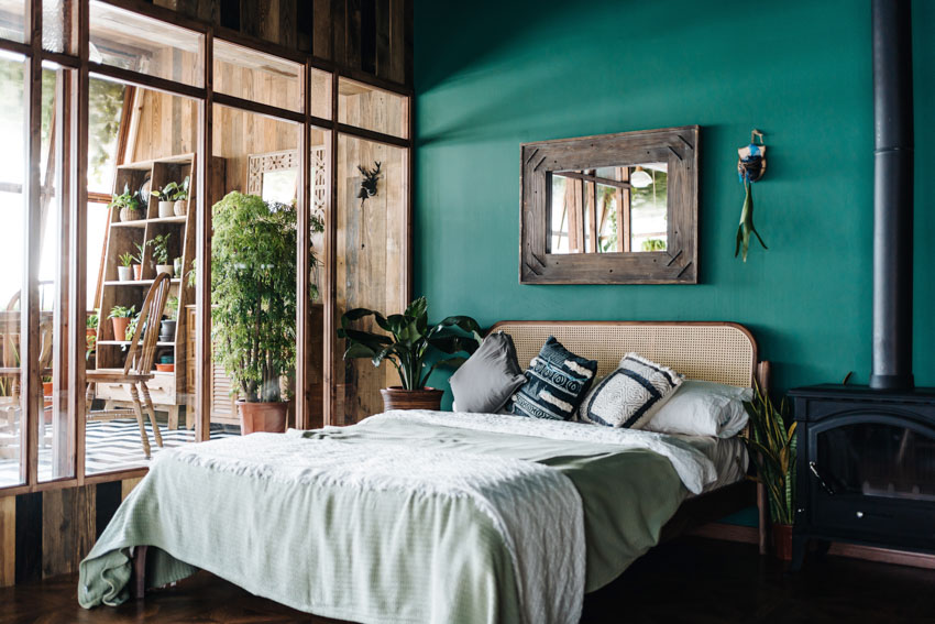 Bedroom with green wall, headboard, pillows, windows, and mirror