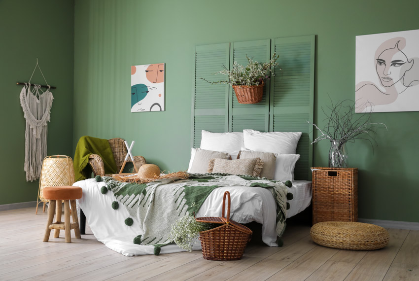 Bedroom with green wall, pillows, bedding, stool, and nightstand