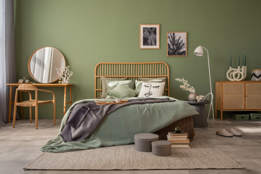Sage green painted bedroom with bamboo headboard and engineered wood chair