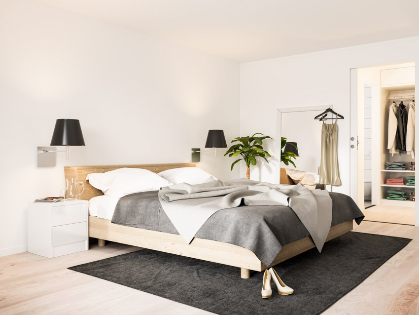 Bedroom with white walls, rug, bedding, nightstands, lamp, and wooden flooring