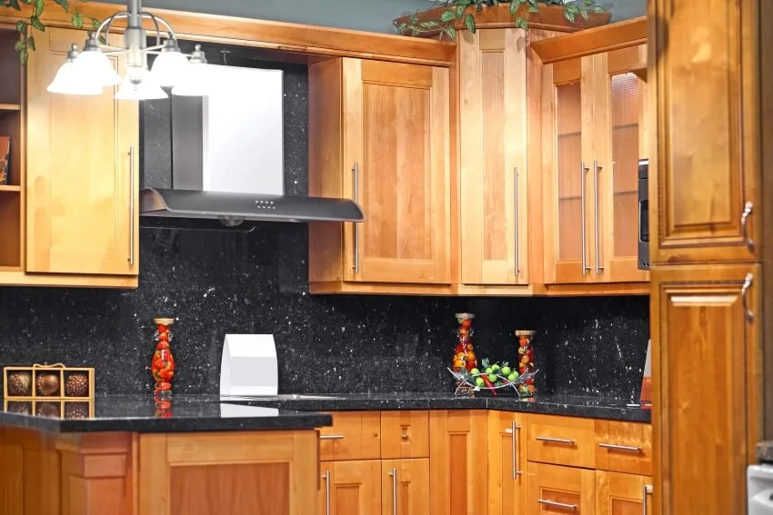 Black granite countertop and backsplash, and a birch cabinets in a kitchen
