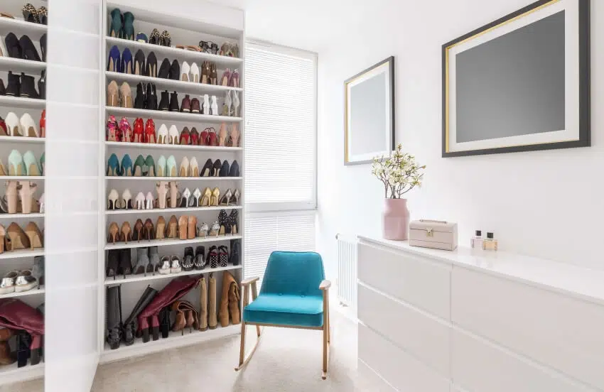 Blue chair in the middle of a room with a dresser and an organized shoes in shelves
