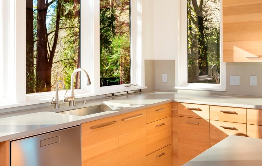Bright kitchen with natural lighting features wood laminate cabinets, granite countertops and undermount sink