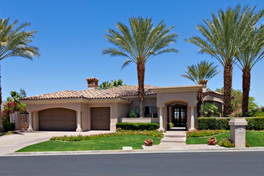 California ranch house with palm trees, garage, driveway, shingle roof, and front door