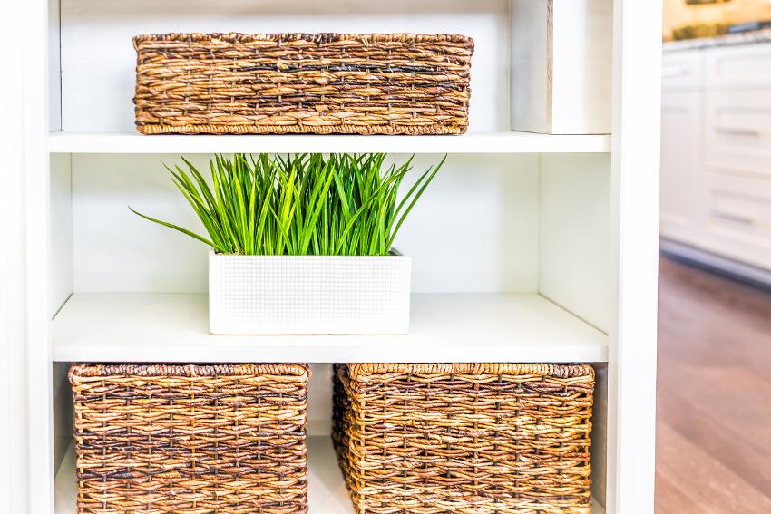 Closeup of white modern minimalist shelves in kitchen with woven baskets and green potted plants