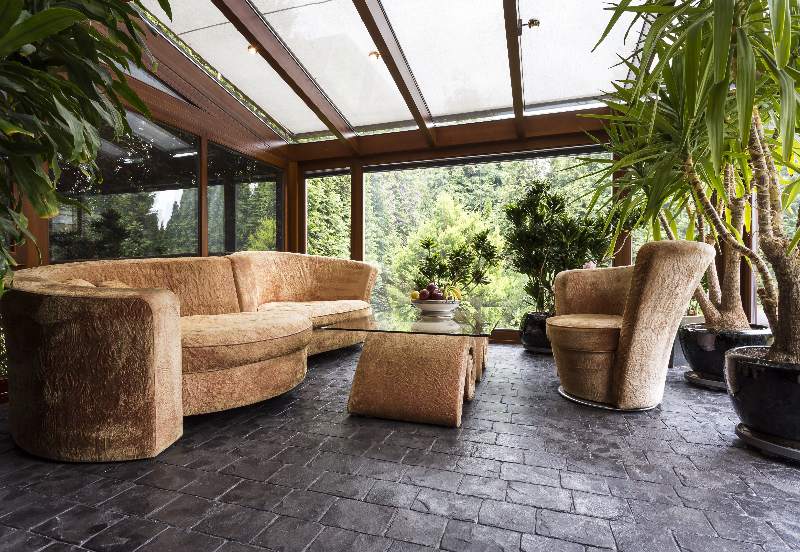 Comfortable plush lounge set in a conservatory with dark laminate flooring