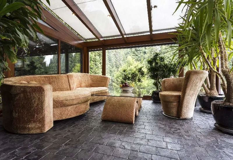 Comfortable plush lounge set in a conservatory with dark laminate flooring