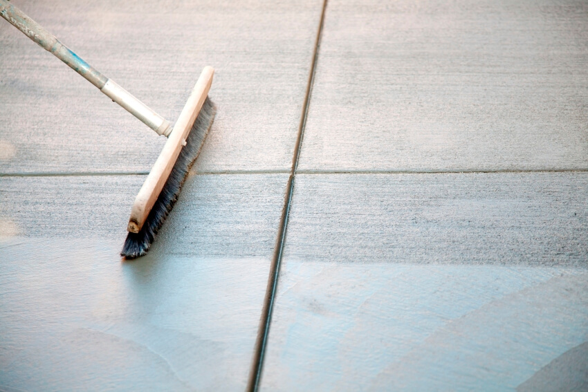 A concrete broom brushing a newly poured concrete