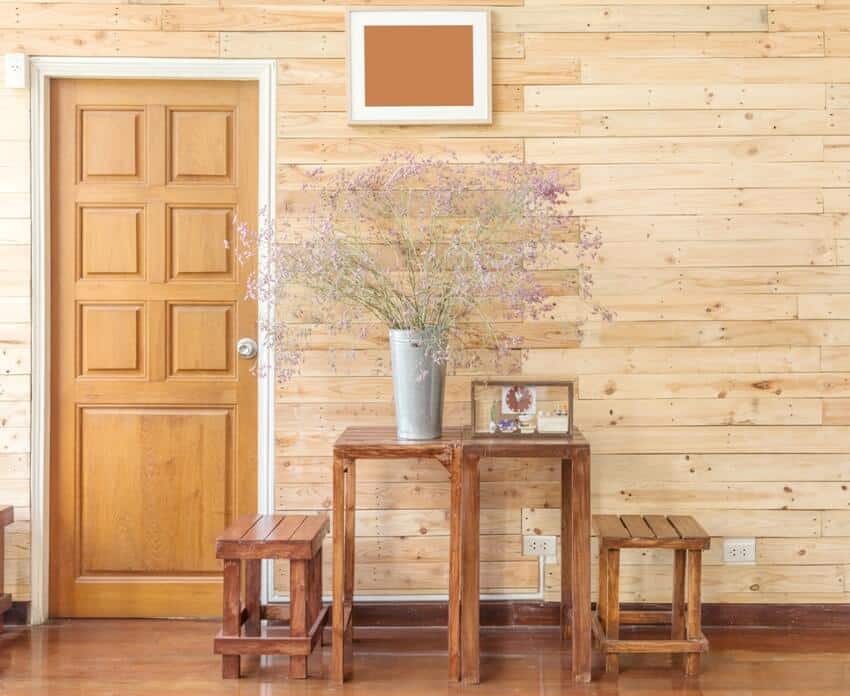 Cozy and warm interior with reclaimed wooden wall, a wooden door table sets and flowers in a vase