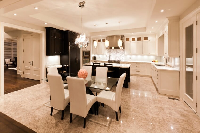 Cream-colored interior of a kitchen and dining room with pendant lights and granite flooring