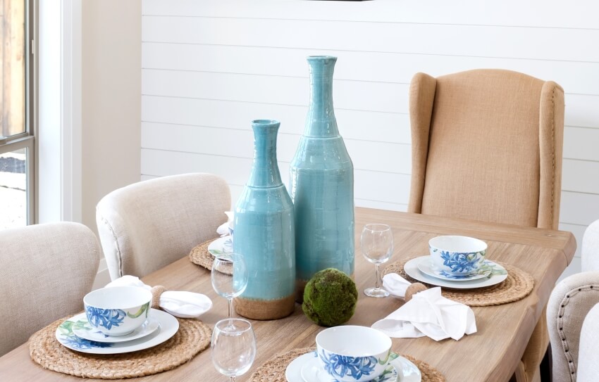 Dining room table setting with blue vase decor and wine glasses in a kitchen with PVC nickel gap shiplap