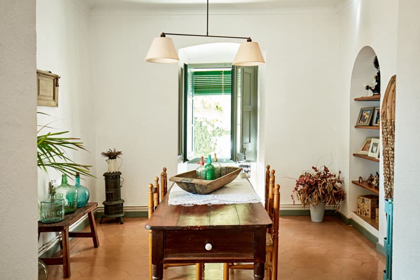 Dining room with ceramic terracotta tile floor, table, chairs, window, shelves, and hanging lights