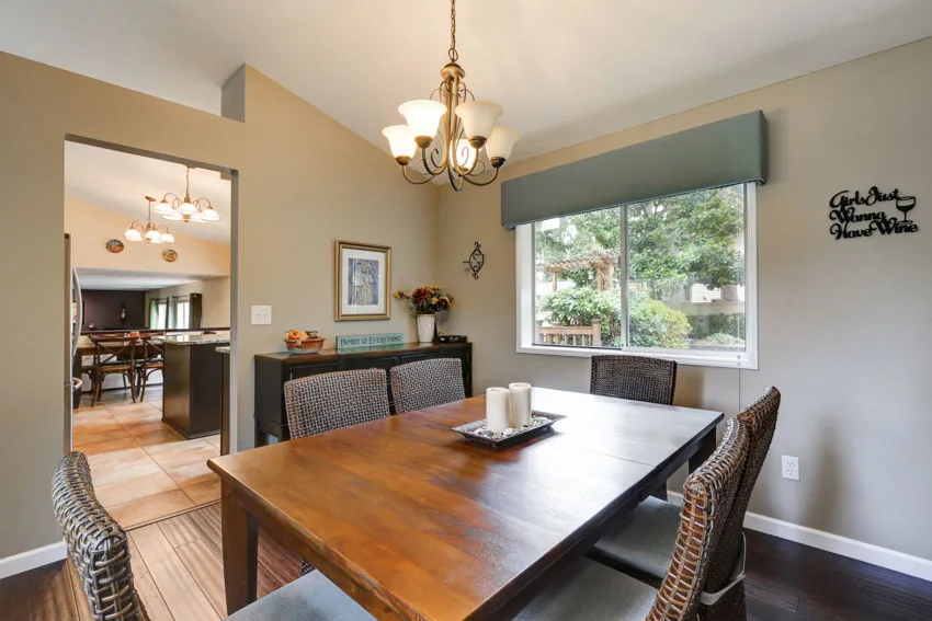 Dining room with taupe walls, table, chairs, window shades, chandelier, and wooden floor