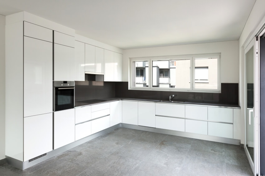 Empty apartment kitchen with black counters and white ceiling height cabinets