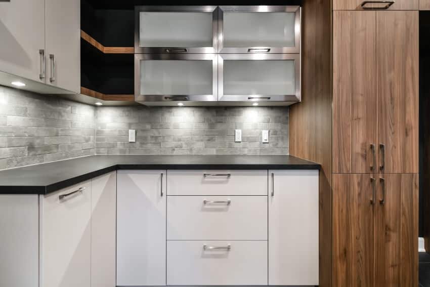 Empty kitchen with aluminum cabinet doors, stone backsplash and under cabinet lighting